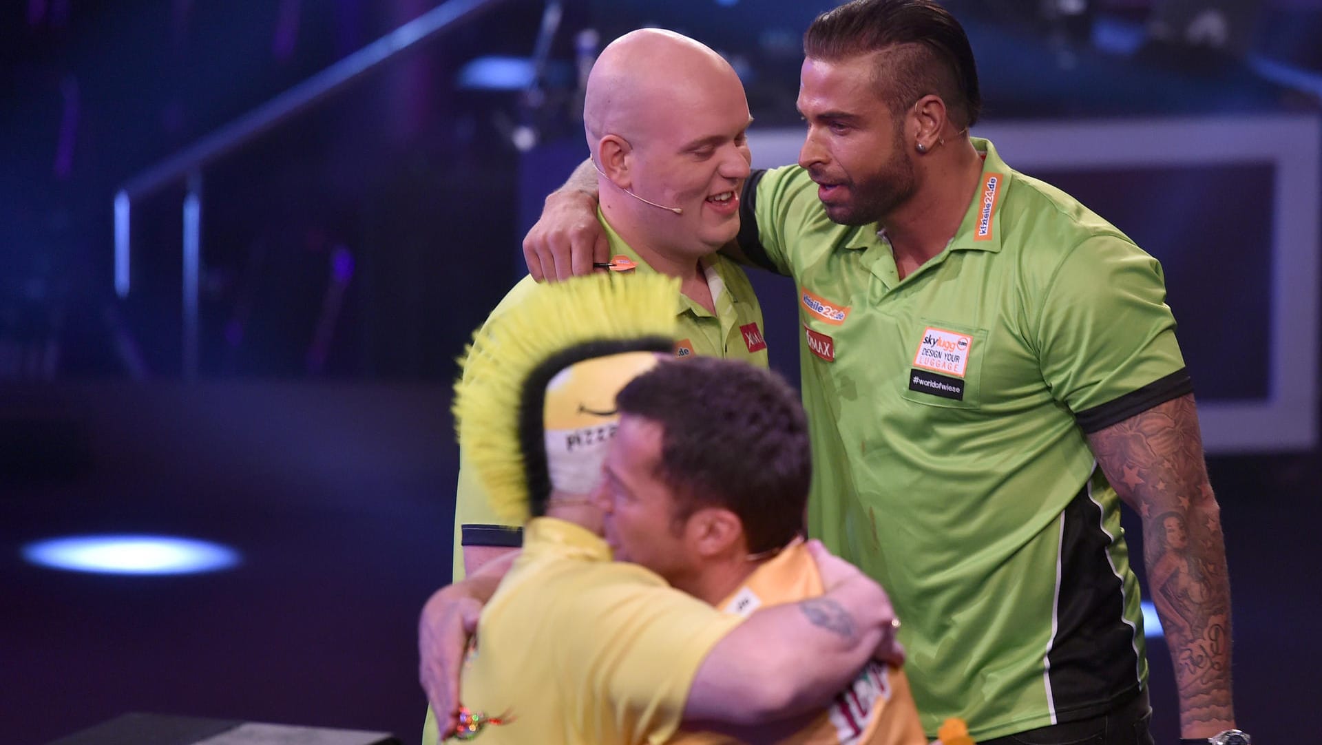 Sieger Tim Wiese umarmt seinen Co-Spieler Michael van Gerwen bei der Promi-Darts-WM 2017. Im Vordergrund die zweitplatzierten Lothar Mattäus und Peter Wright.