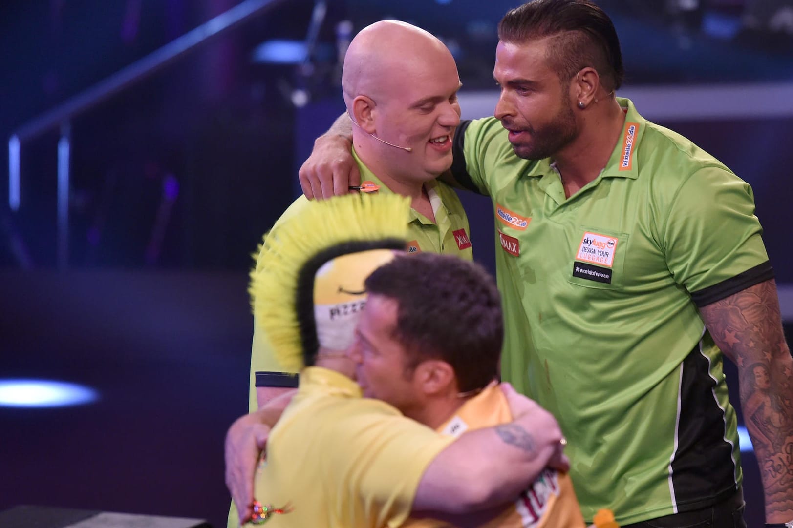 Sieger Tim Wiese umarmt seinen Co-Spieler Michael van Gerwen bei der Promi-Darts-WM 2017. Im Vordergrund die zweitplatzierten Lothar Mattäus und Peter Wright.