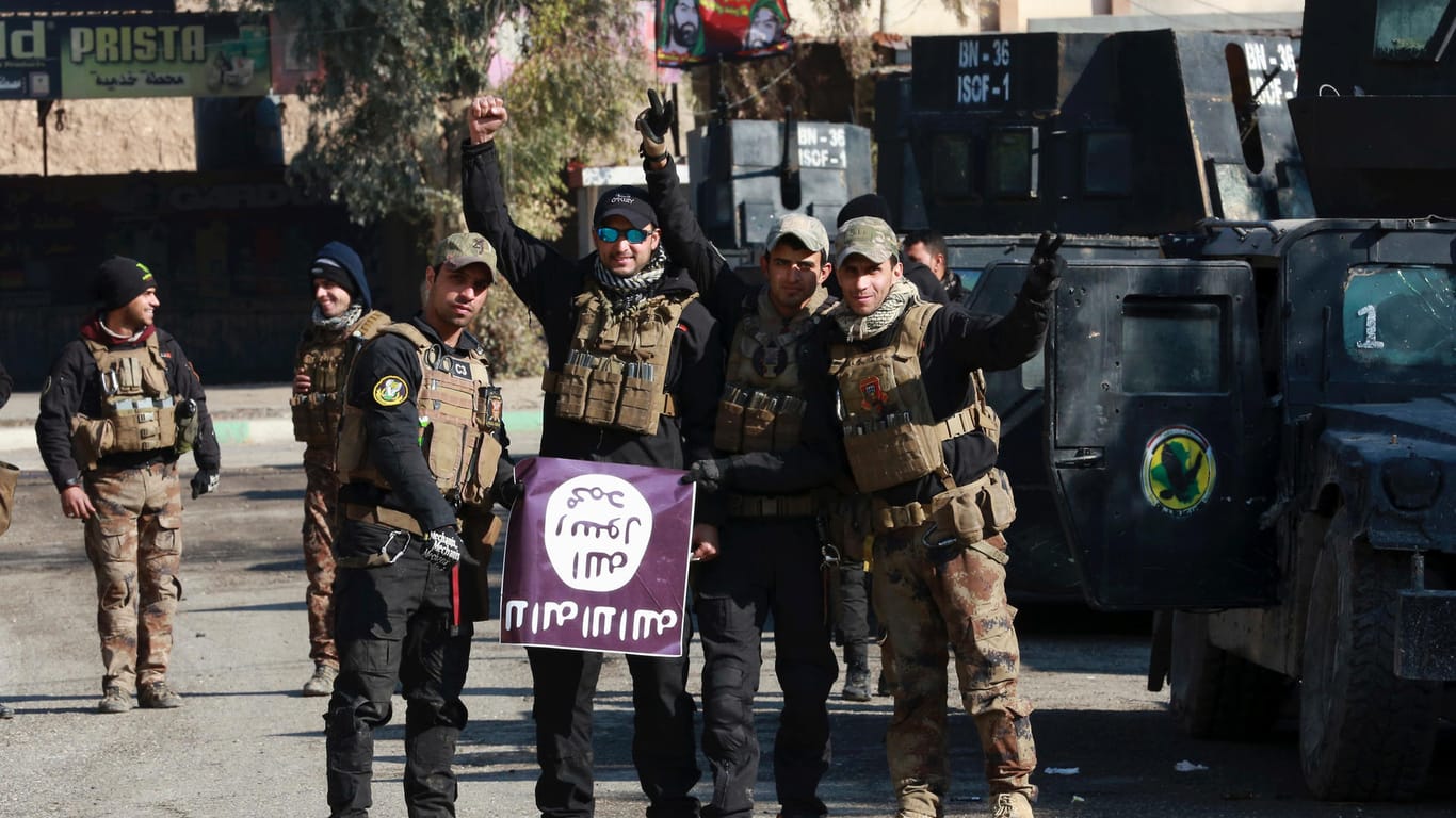 Sieg über den IS: Irakische Spezialkräfte halten eine Fahne der Terrormiliz Islamischer Staat in den Händen.