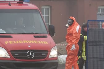 Ein Feuerwehrmann im Schutzanzug steht in der Nähe von Steinburg vor einer Geflügelzucht.