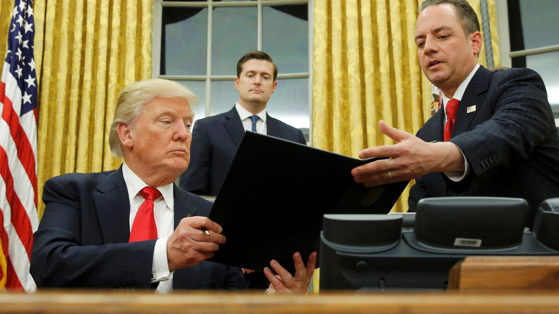US-Präsident Donald Trump überreicht sein Dekret gegen "Obamacare" seinem Stabs-Chef Reince Priebus. Rob Porter (Mitte) guckt zu. US-Präsident Donald Trump überreicht sein Dekret gegen "Obamacare" seinem Stabs-Chef Reince Priebus. Rob Porter (Mitte) guckt zu.