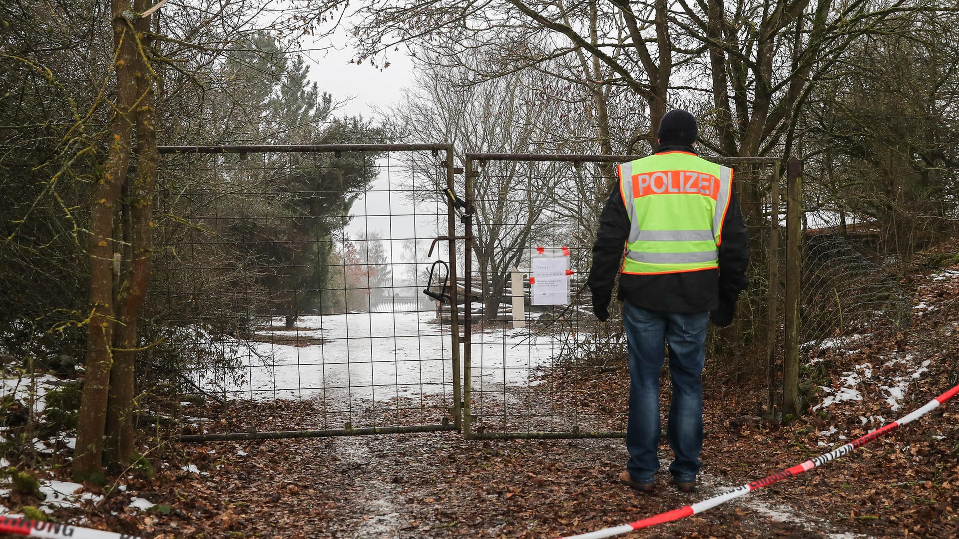 Ein Polizist vor der abgesperrten Zufahrt zu einem privaten Grundstück in der Nähe von Arnstein bei Würzburg.
