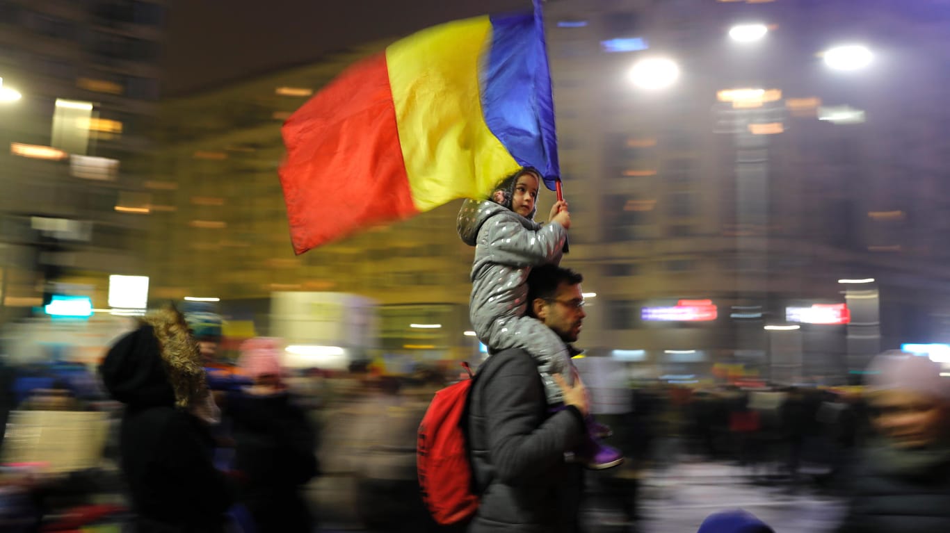 Ein Demonstrant in Bukarest trägt sein Kind mit der rumänischen Flagge auf den Schultern.