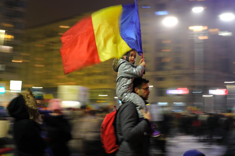 Ein Demonstrant in Bukarest trägt sein Kind mit der rumänischen Flagge auf den Schultern.