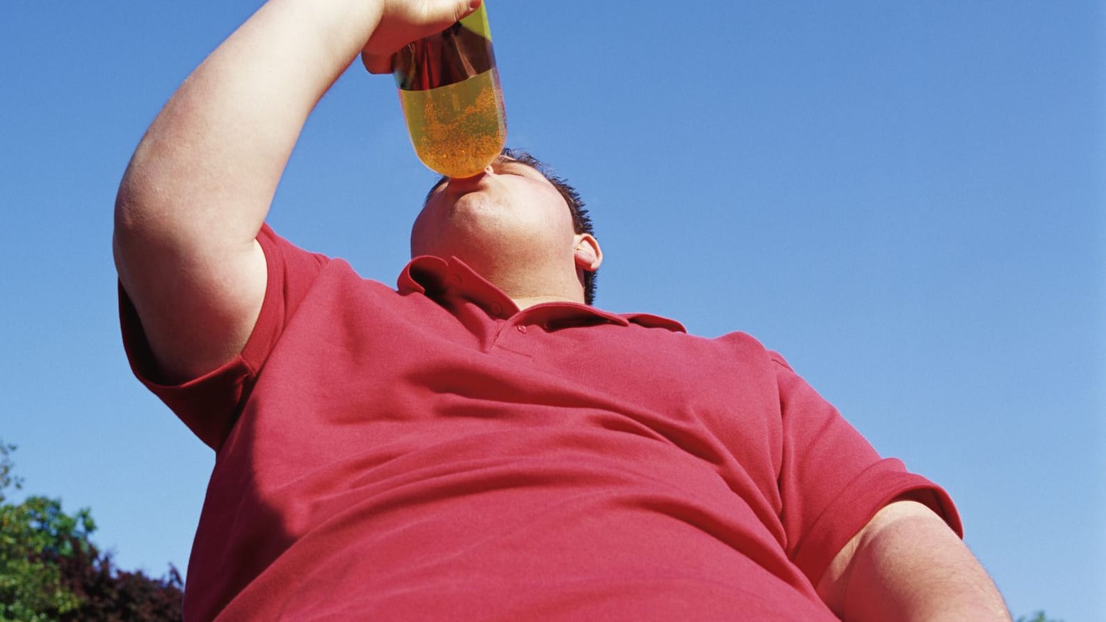 Übergewichtiger Junge trinkt Flasche Limonade