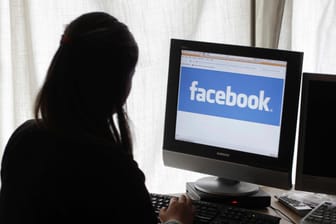 Fake-News: Junge Frau sitzt an ihrem Computer und surft auf Facebook.