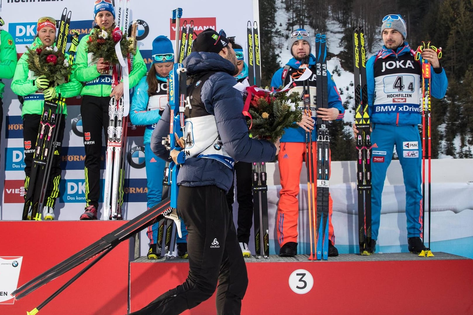 Vorzeitiger Abgang: Der Franzose Martin Fourcade (vorne) verließ die Siegerehrung aus Protest gegen das russische Team (im Hintergrund).