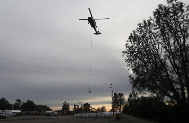 Ein Hubschrauber fliegt Steinsäcke zu den beschädigten Überläufen am Oroville-Staudamm.