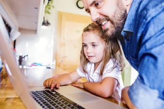 Tochter und Vater sitzen vor einem Laptop (Symbolfoto)