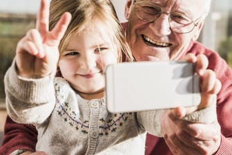 Großvater und Enkelin nehmen ein Selfie mit einem Smartpone auf.