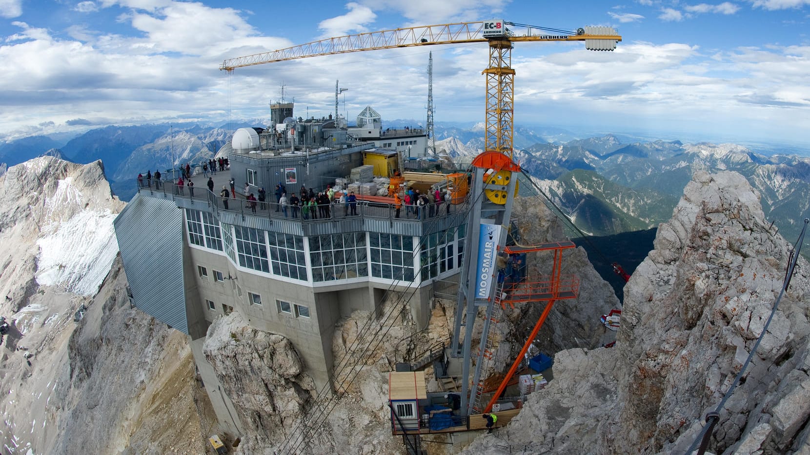 Die Materialseilbahn und der Baukran sind auf der Zugspitze vom Gipfelkreuz aus zu sehen.