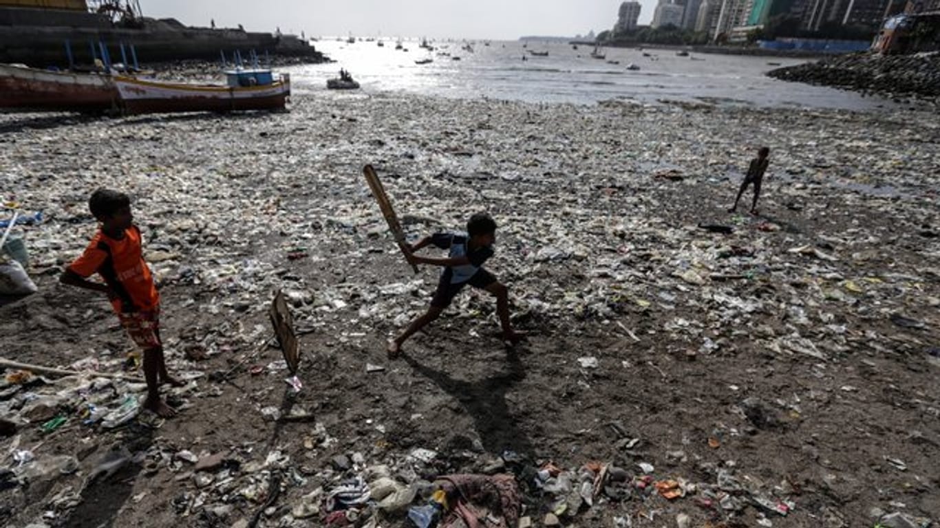 Indische Kinder spielen in Mumbai an einem Strand, an dem Plastikmüll und anderer Unrat aus dem Meer, angespült wurde.