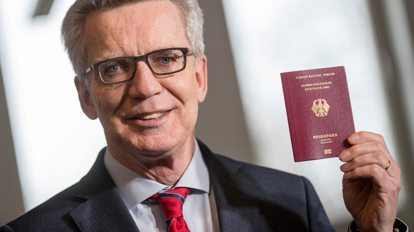 Thomas de Maiziere zeigt ein Musterexemplar des neuen Reisepasses für Deutschland.