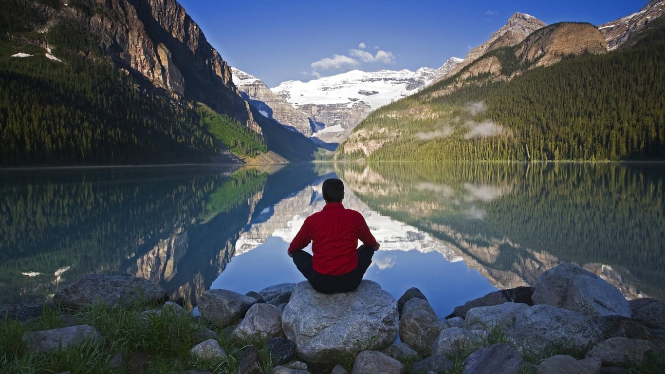 Mann meditiert am Lake Louise Alberta in Kanada.