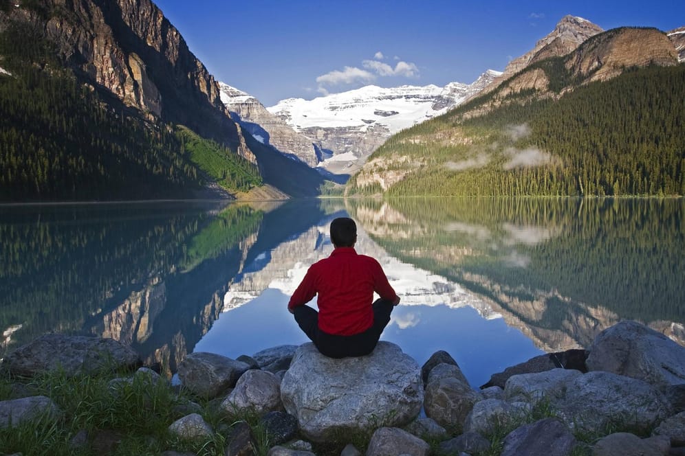 Mann meditiert am Lake Louise Alberta in Kanada.