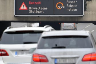 Autos fahren in Stuttgart durch die Innenstadt unter einer Anzeige für die Umweltzone entlang