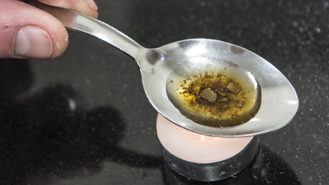 Ein Mann "kocht" sich auf einem Löffel die Dosis für einen Schuss Heroin. Ein Mann "kocht" sich auf einem Löffel die Dosis für einen Schuss Heroin.