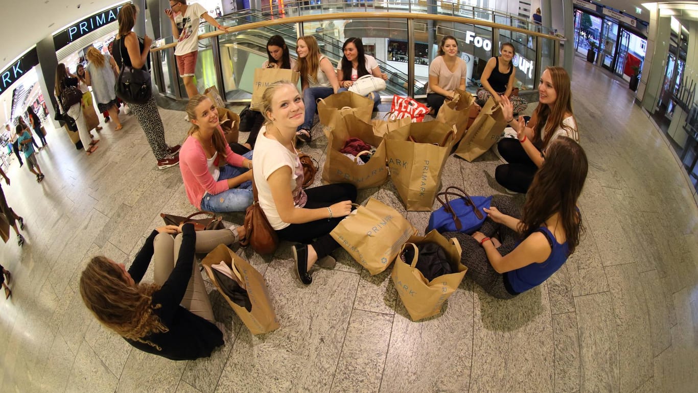 Jugendliche sitzen in einem Einkaufszentrum auf dem Boden