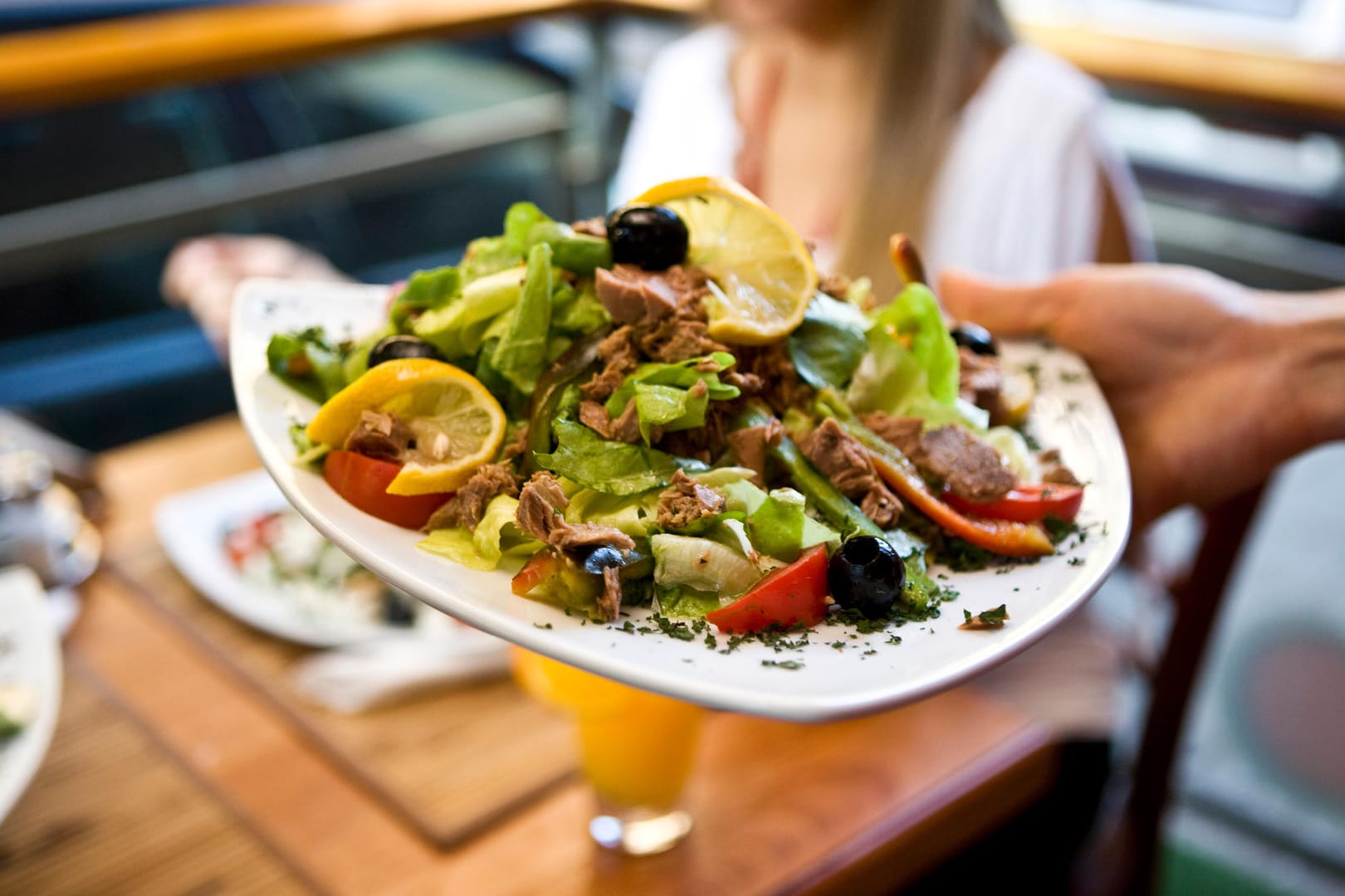 Einer Frau wird ein mediterraner Salat serviert.