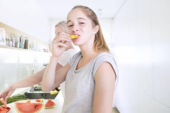 Eine Jugendliche beist genüsslich in ein Stück Melone.