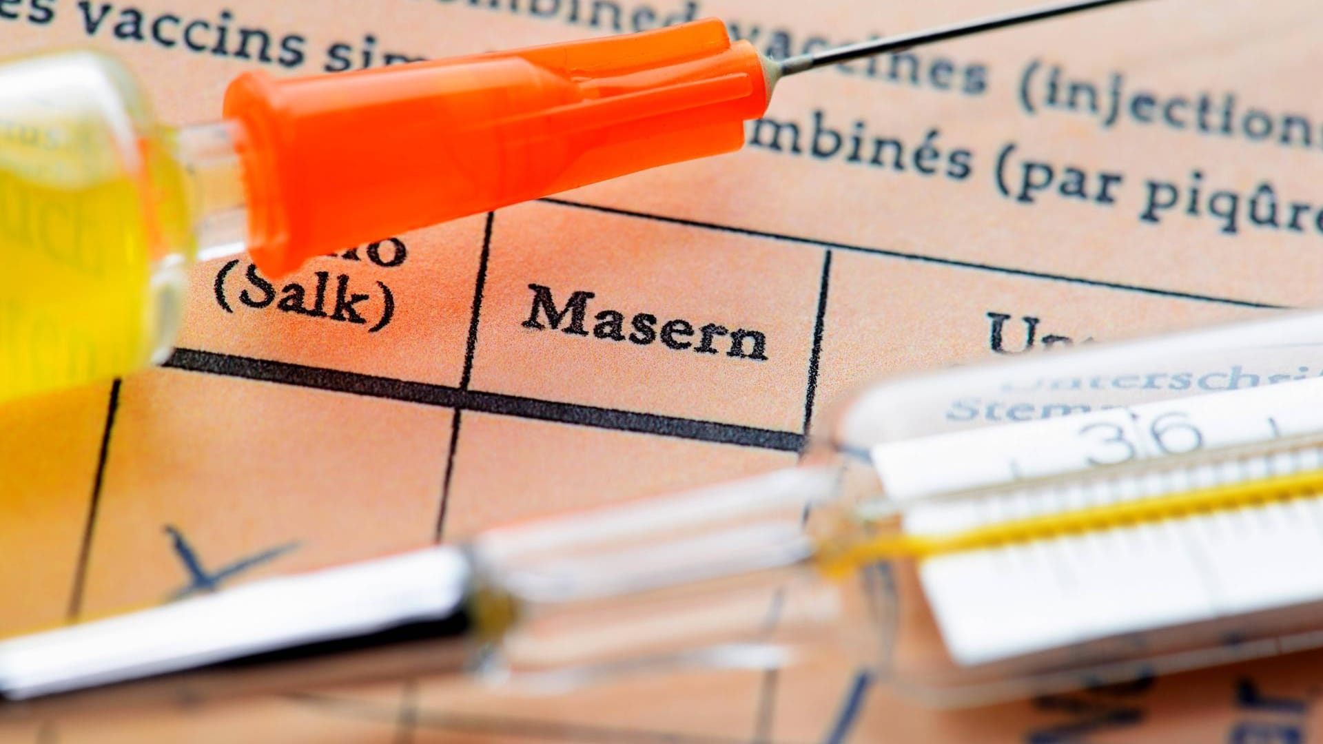 Masern: Eine Impfspritze liegt auf einem Impfausweis