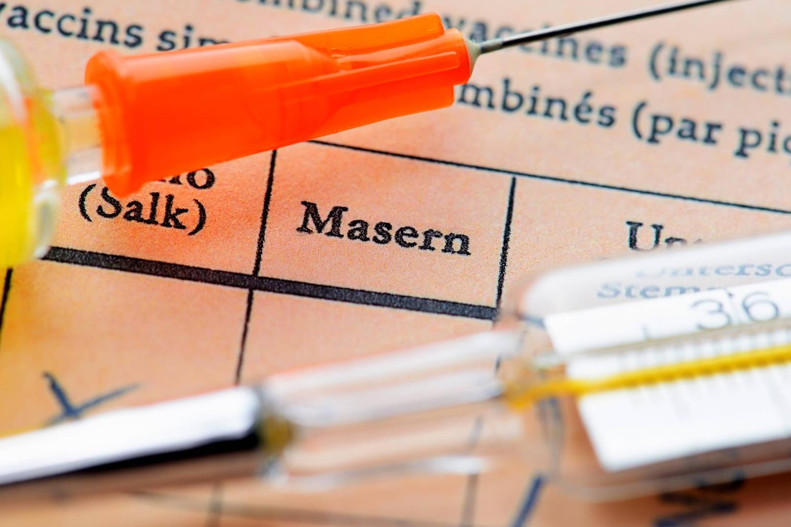 Masern: Eine Impfspritze liegt auf einem Impfausweis