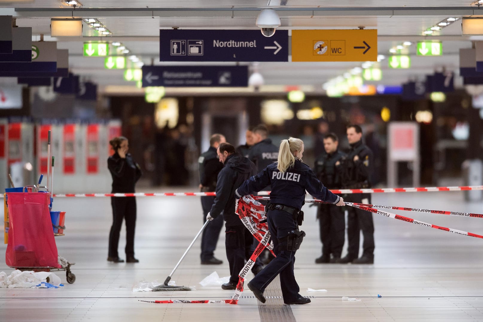 Polizisten entfernen am Freitag nach Mitternacht im Hauptbahnhof von Düsseldorf (Nordrhein-Westfalen) die Absperrbänder. Am Morgen nach dem Amoklauf läuft der Pendlerverkehr wieder, als wäre nichts gewesen.