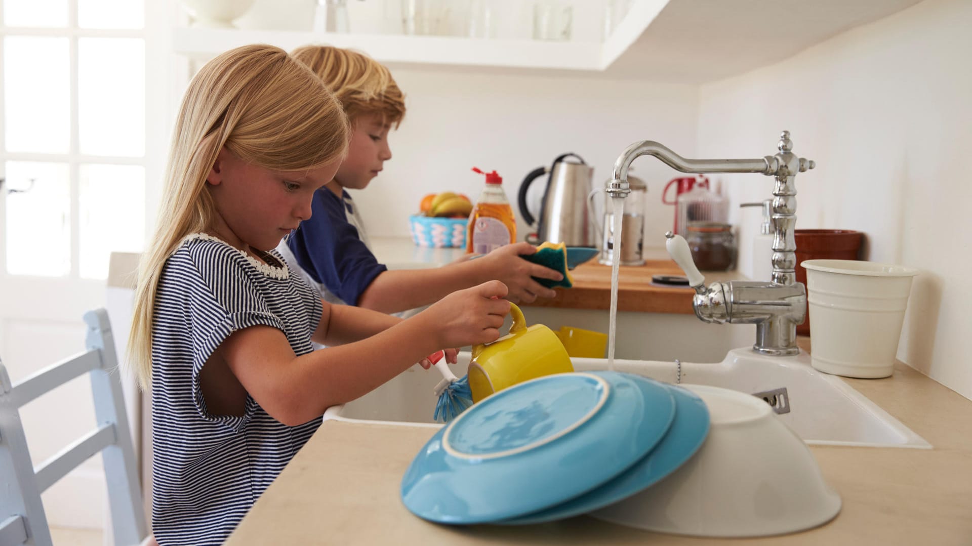 Ein Geschwisterpaar spült Geschirr ab: Hausarbeit ist bei Kindern nicht unbedingt beliebt. Aber es ist sinnvoll, dass sie ihre Eltern unterstützen.