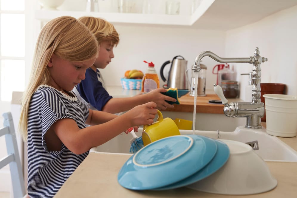 Ein Geschwisterpaar spült Geschirr ab: Hausarbeit ist bei Kindern nicht unbedingt beliebt. Aber es ist sinnvoll, dass sie ihre Eltern unterstützen.