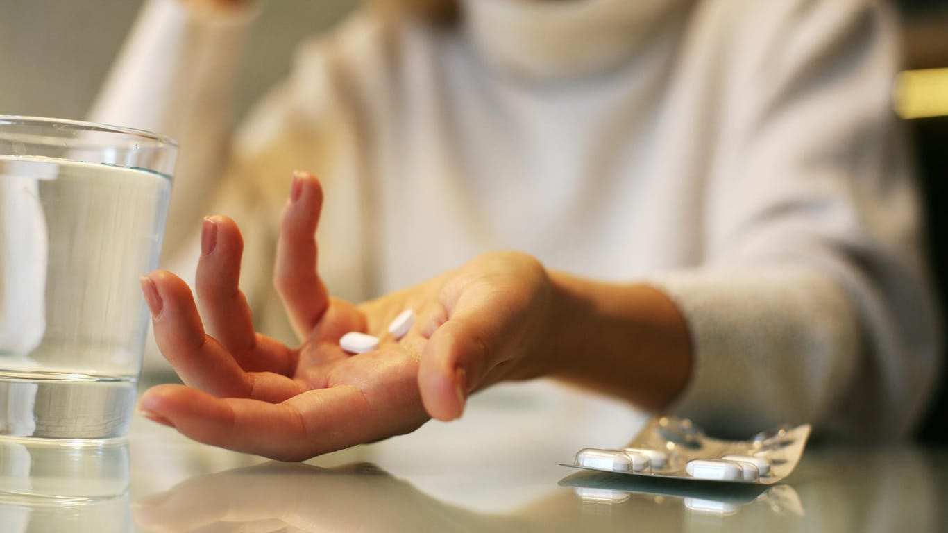 Eine Frau hat einige Tabletten in ihrer Hand liegen.