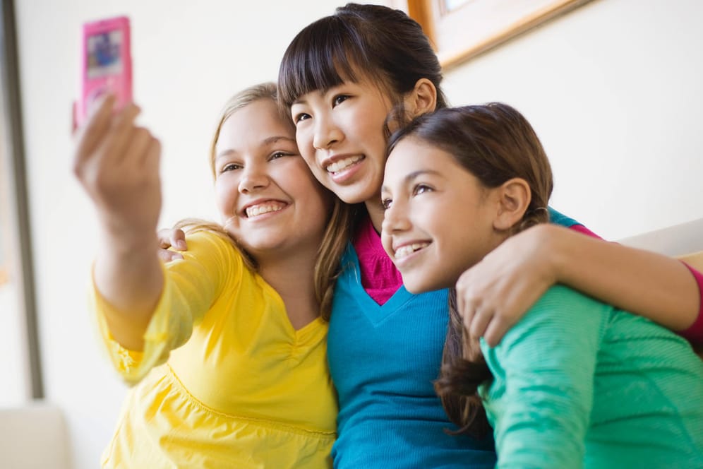 Drei junge Mädchen machen zusammen ein Selfie.