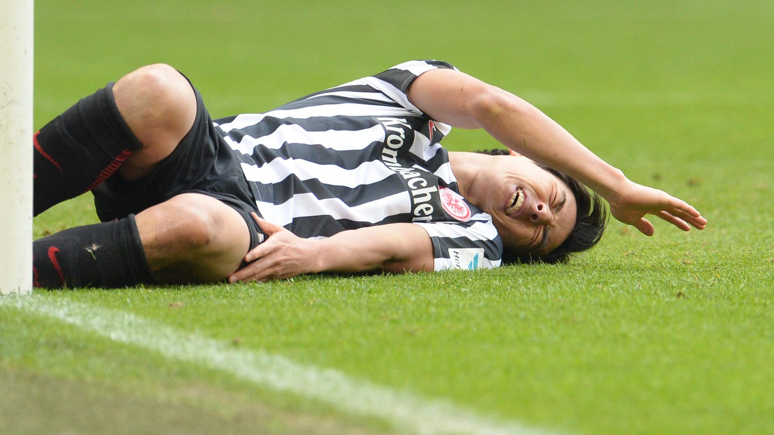 Eintrachts Makoto Hasebe liegt nach dem Pfostenpraller auf dem Rasen.