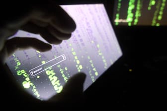 Symbolfoto zum Thema Internetkriminalitaet Eine Hand vor einem Computer Monitor mit Passwort Eingab