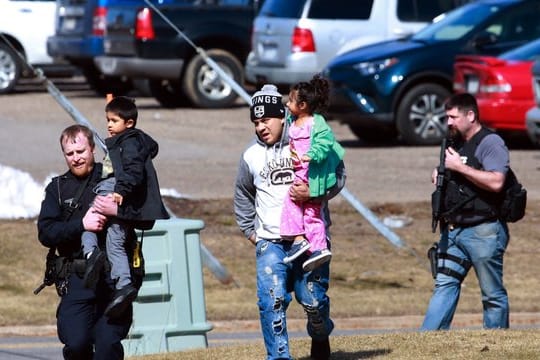 Polizisten eskortieren in Rothschild (USA) eine Familie aus einem Wohnhaus.