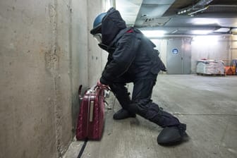 Ein verdächtiger Koffer wird von einem Bombenentschärfer untersucht.