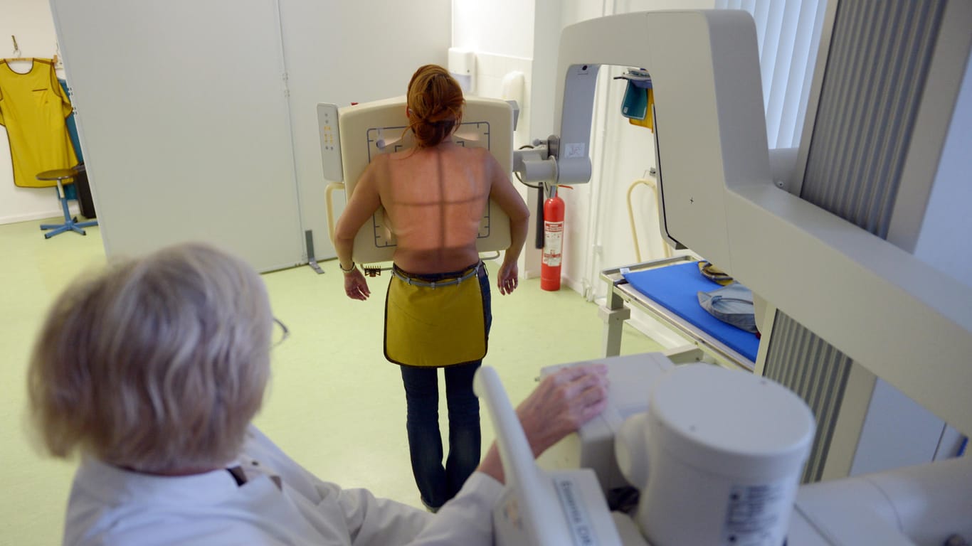 Eine Radiologieassistentin bereitet eine Frau für eine Röntgenaufnahme vor.