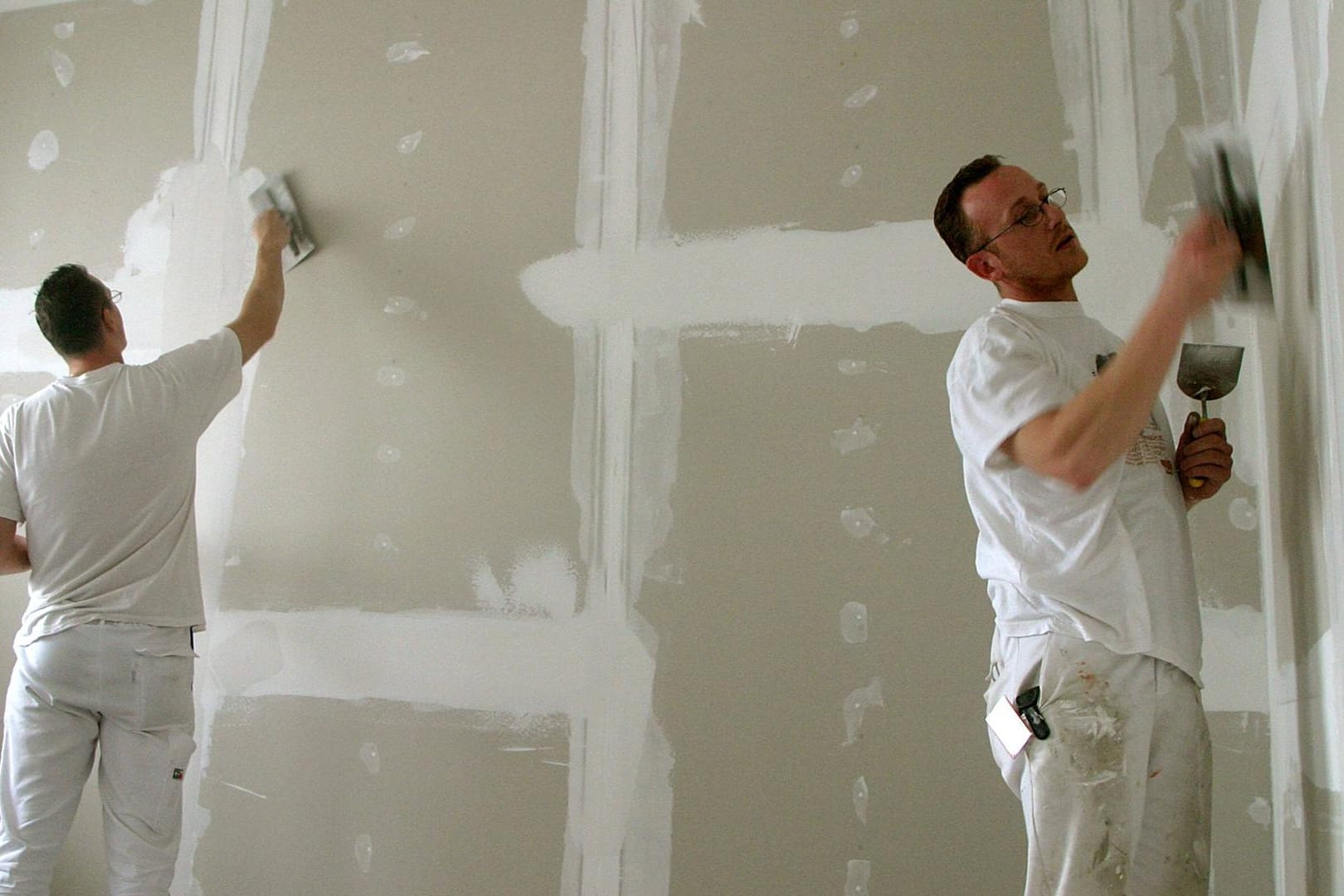 Maler verspachtelt eine Gipskartonwand: Mit etwas Geschick können Sie aus einem großen Raum zwei Zimmer machen.