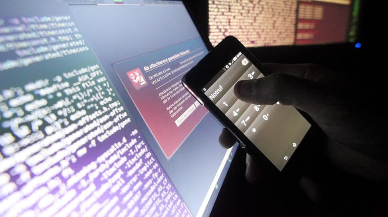 Symbolfoto zum Thema Internetkriminalitaet Ein Mann haelt ein Smarthone mit Notrufeinstellung vor e