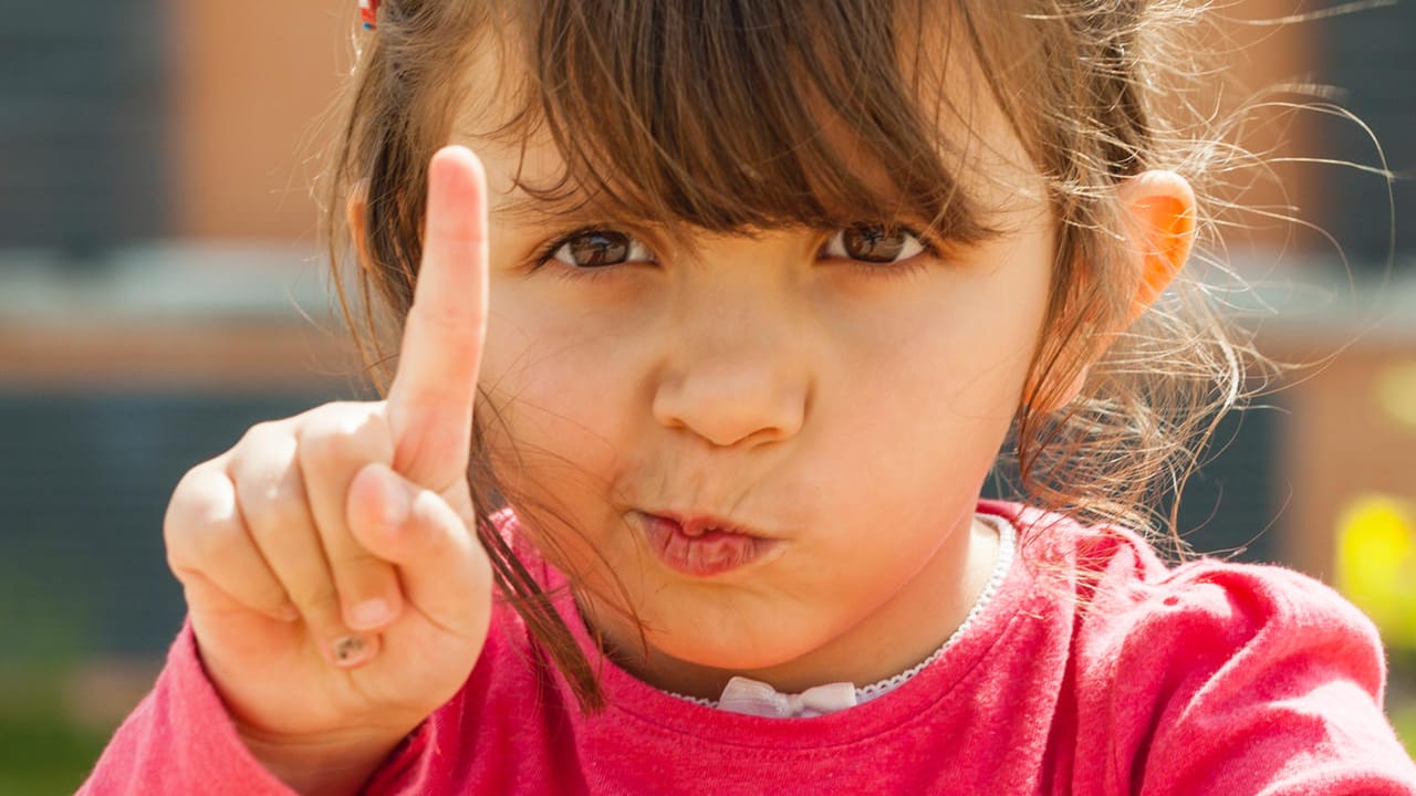 Ein Kind hebt den Zeigefinger: Manche Kinder legen ein besserwisserisches Verhalten an den Tag.