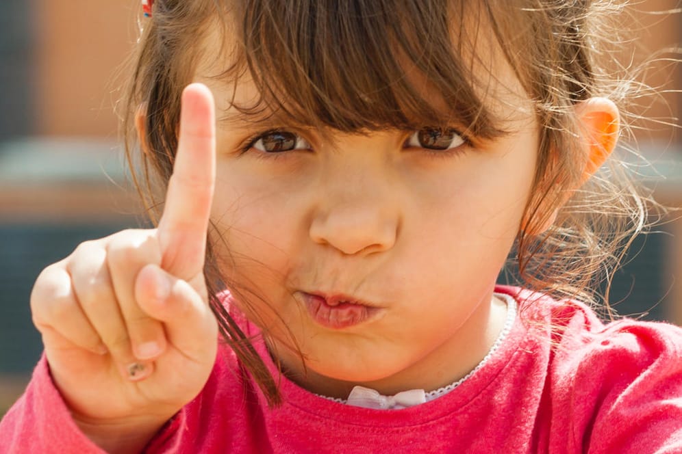 Ein Kind hebt den Zeigefinger: Manche Kinder legen ein besserwisserisches Verhalten an den Tag.