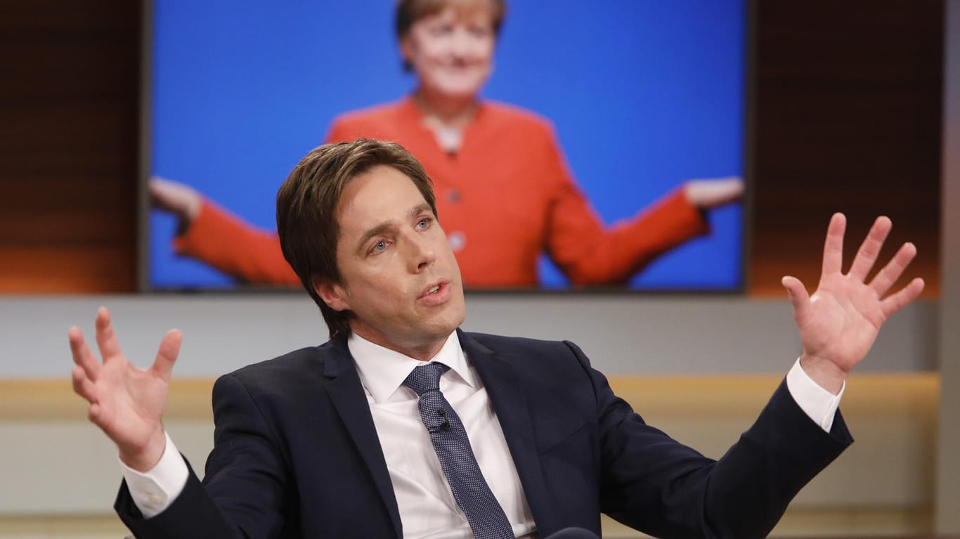 Bei Anne Will: "Spiegel"-Reporter Markus Feldenkirchen vor einem Fernseher, auf dem gerade Angela Merkel zu sehen ist.