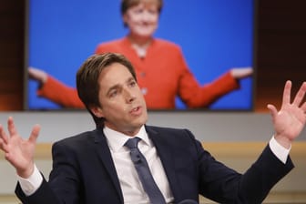 Bei Anne Will: "Spiegel"-Reporter Markus Feldenkirchen vor einem Fernseher, auf dem gerade Angela Merkel zu sehen ist.