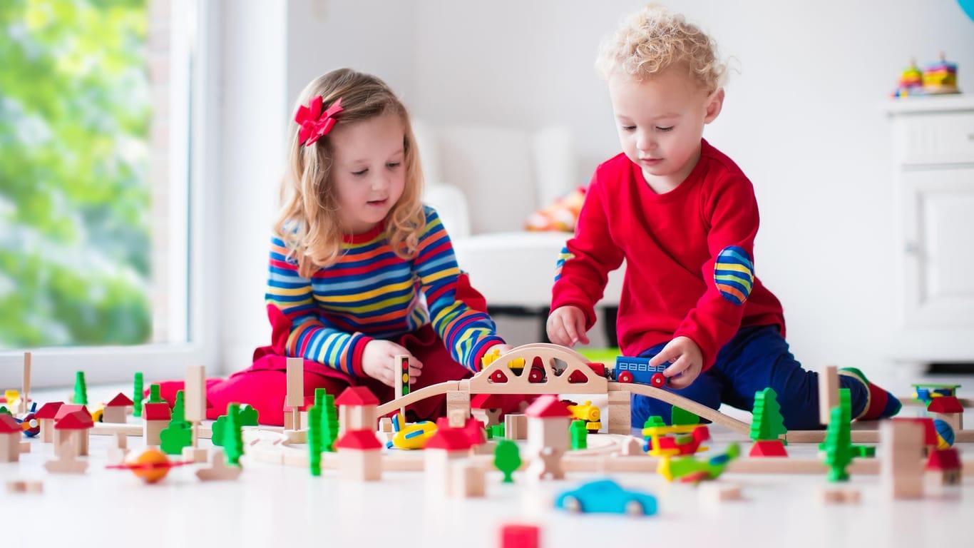 Zwei Kinder spielen mit einem Holzzug: Spielen ist wichtig für die Entwicklung von Kindern.