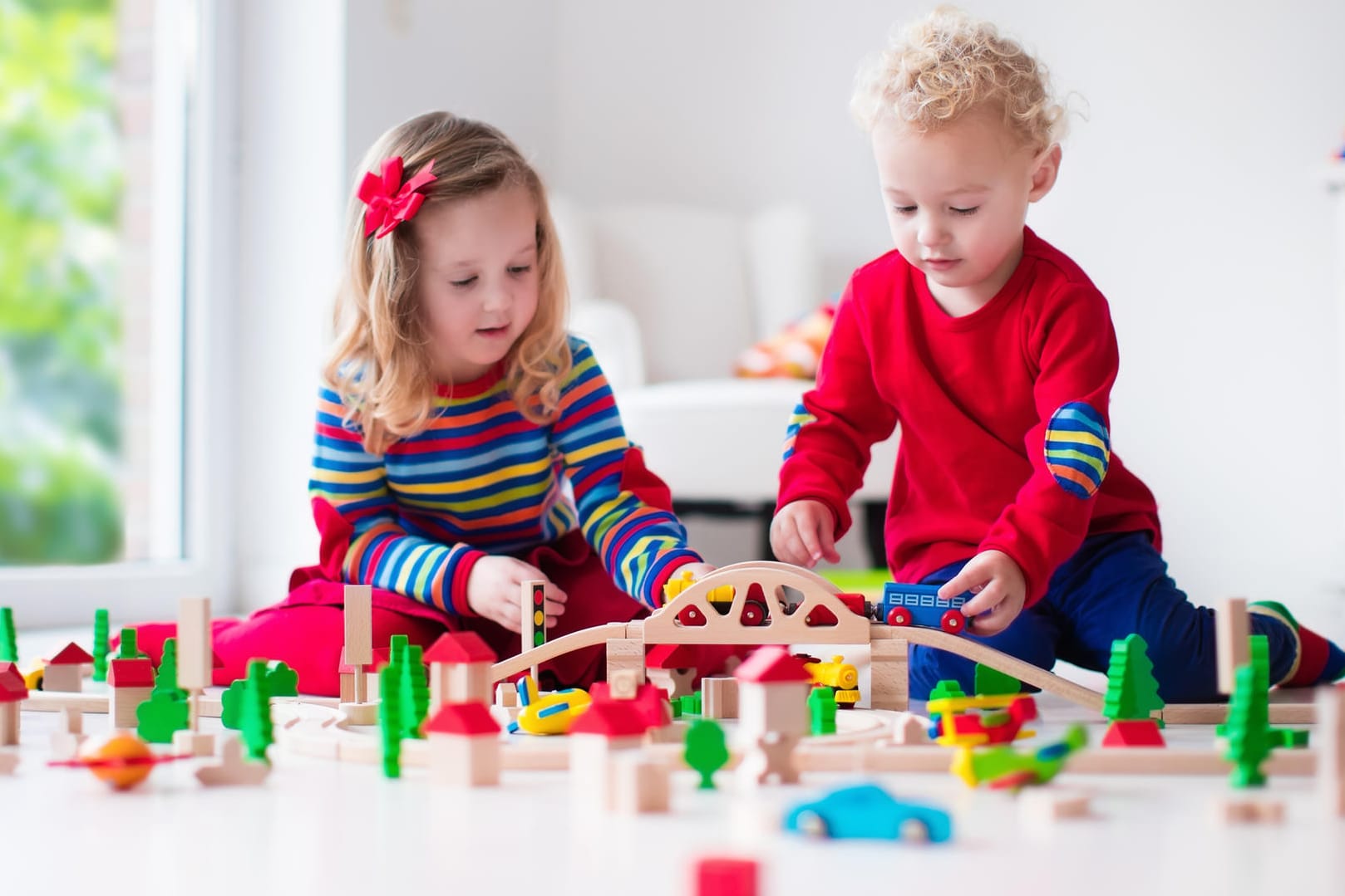 Zwei Kinder spielen mit einem Holzzug: Spielen ist wichtig für die Entwicklung von Kindern.