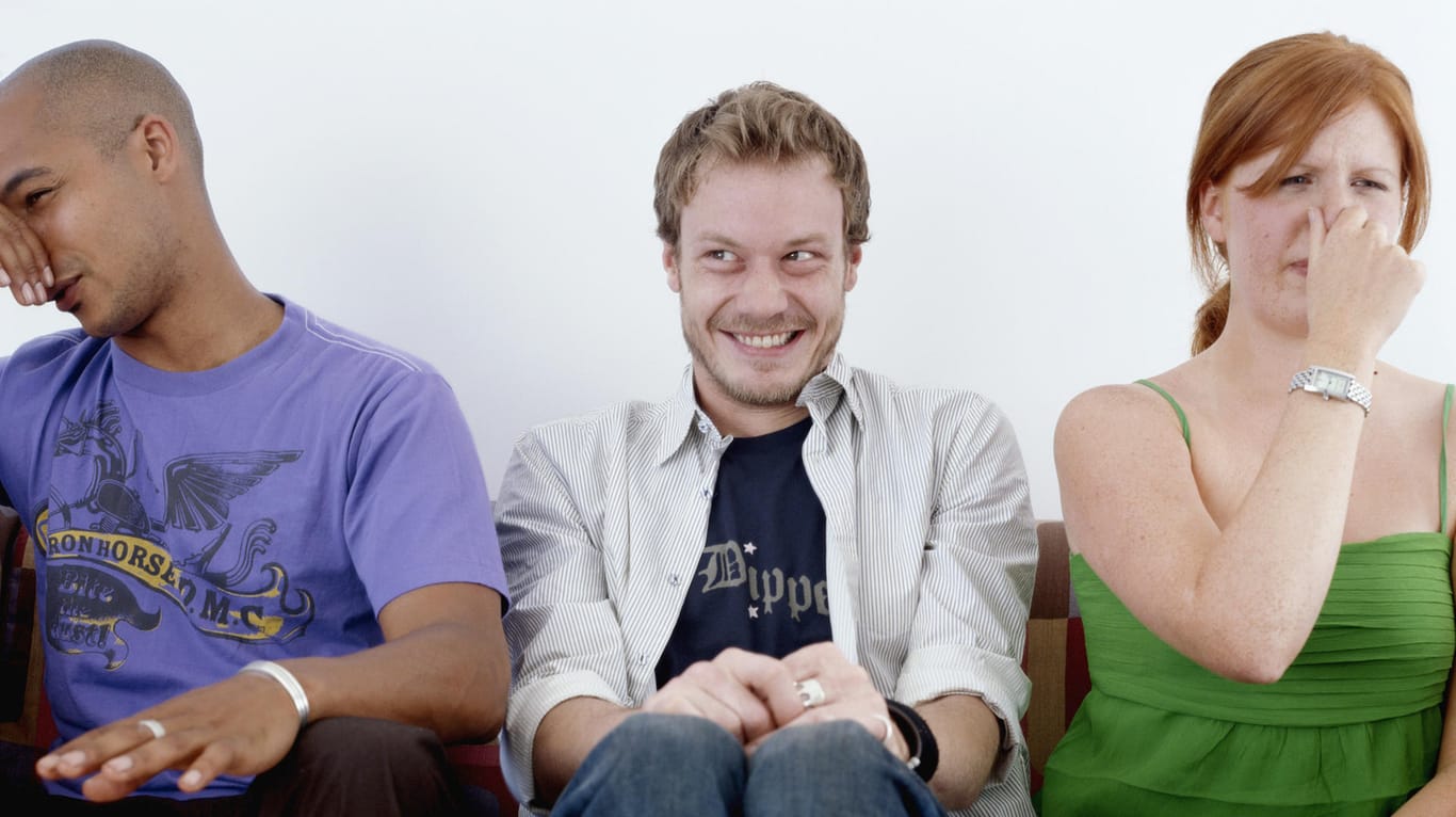 Ein Mann sitzt zwischen zwei Menschen und lacht