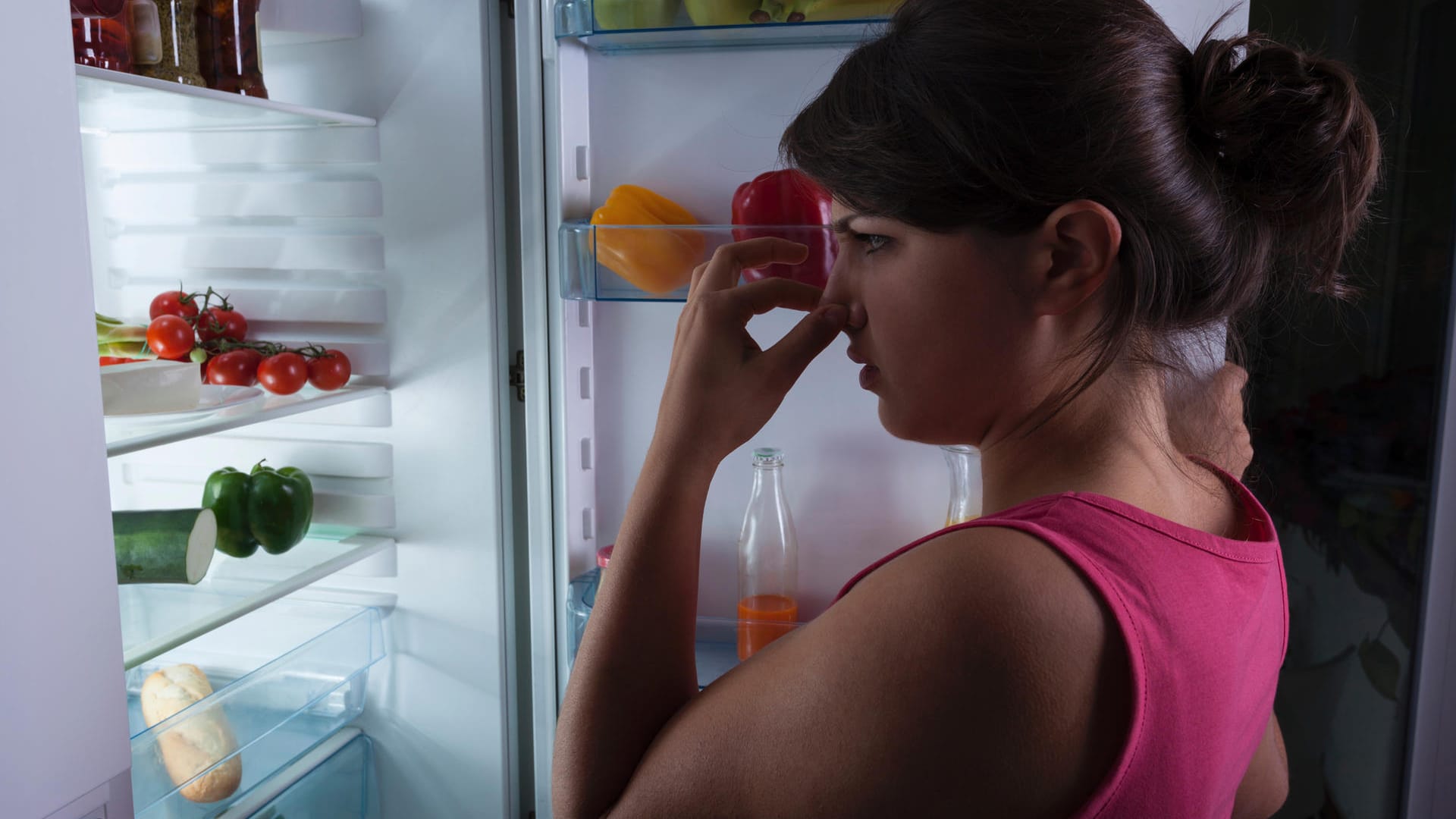 Eine Frau steht vor einem Kühlschrank und hält sich die Nase zu