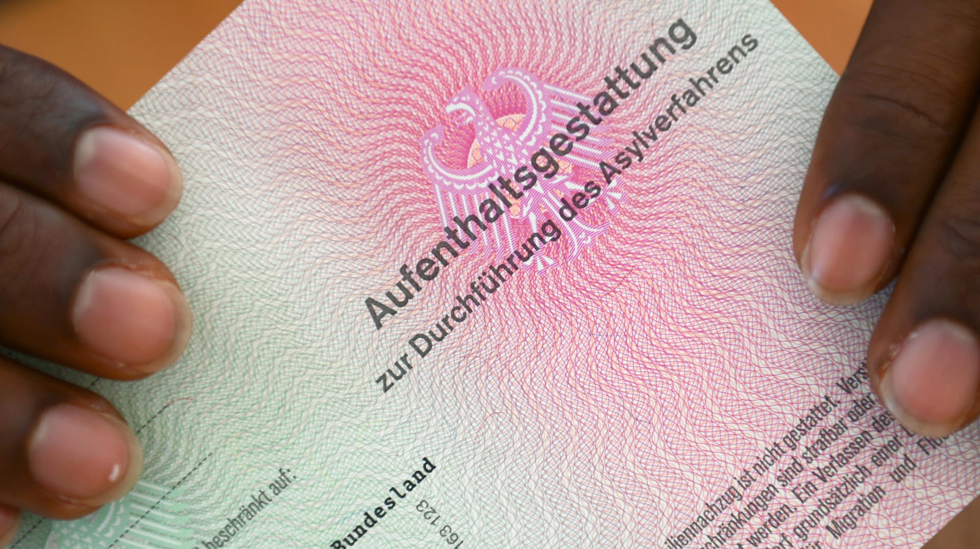 Aufenthaltsgestattung: Ein Asylbewerber hält das wichtige Dokument in Händen.