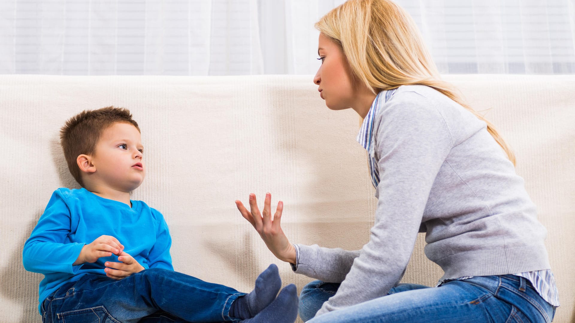 Eine Mutter sitzt mit ihrem Sohn auf dem Sofa.