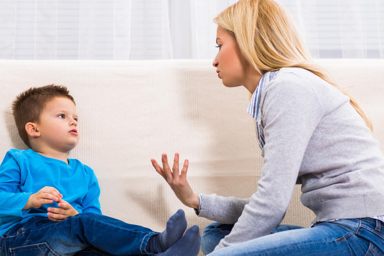 Eine Mutter sitzt mit ihrem Sohn auf dem Sofa.