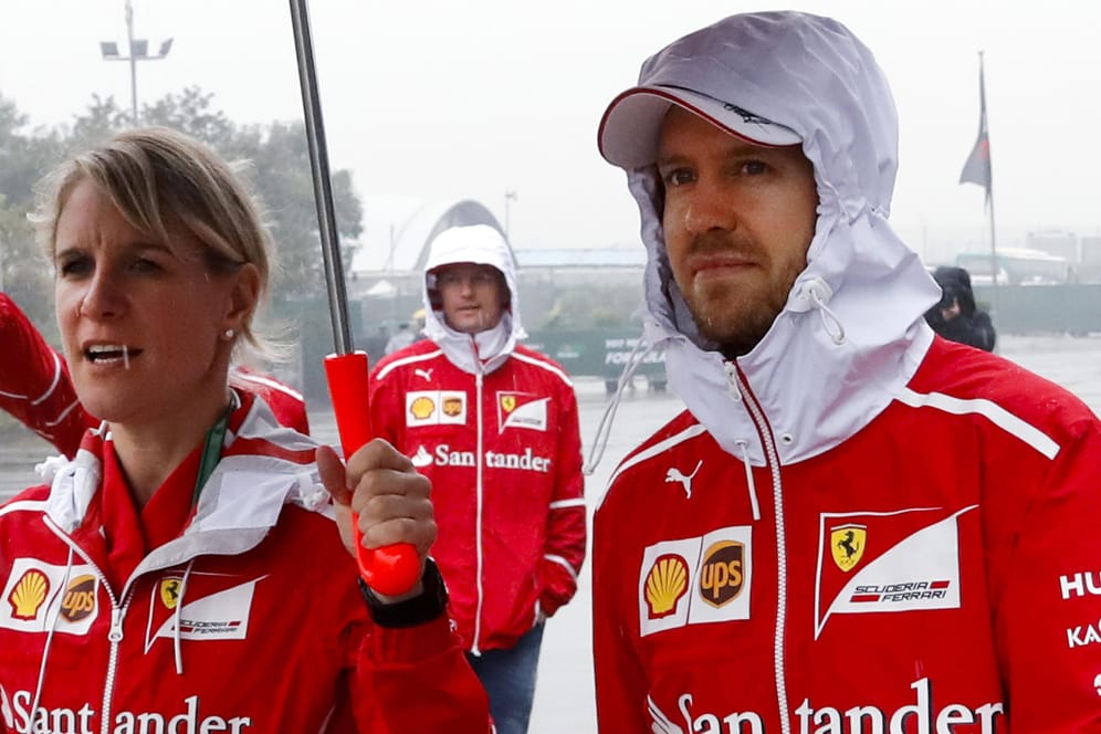 Ferrari-Fahrer Sebastian Vettel steht mit seiner Pressesprecherin Britta Roeske unter einem Schirm im Regen.